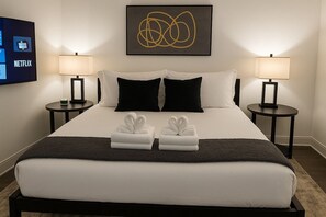 Una camera d'albergo con un letto, due comodini, una TV che mostra il logo di Netflix e un'opera d'arte a parete.