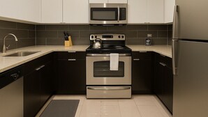 A modern kitchen with stainless steel appliances, including a microwave, oven, and refrigerator. - Chic Studio in Historic Hyde Park – Walk to Campus (Chicago)