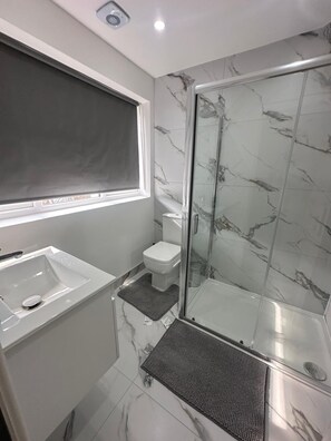 A bathroom with a shower, toilet, and sink. - Studio Apartment Sleeps 1 with Wifi near city (London)
