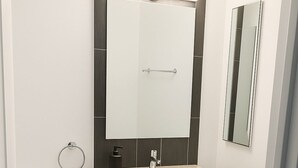 A bathroom with a toilet, a sink, a mirror, and a towel rack. - Bright South Hyde Park Studio (Chicago)