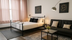 A modern bedroom with a bed, bedside tables, a sofa, and artwork on the walls. - Bright South Hyde Park Studio (Chicago)