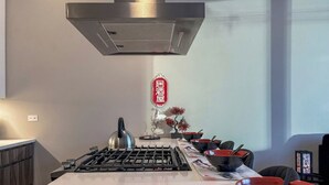 Una cocina con una isla central, estufa a gas y extractor de acero inoxidable.