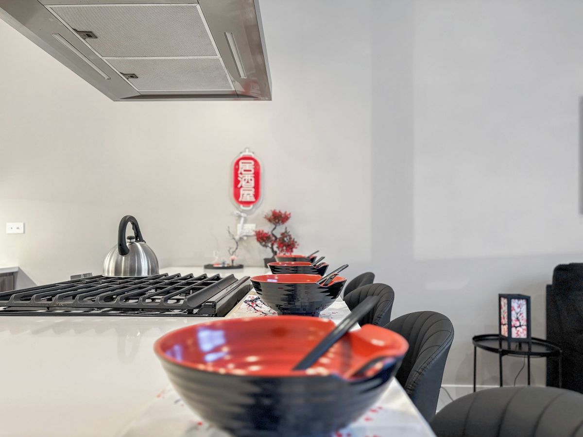 Uma cozinha moderna com fogão a gás, chaleira e área de jantar com mesa posta para dois.