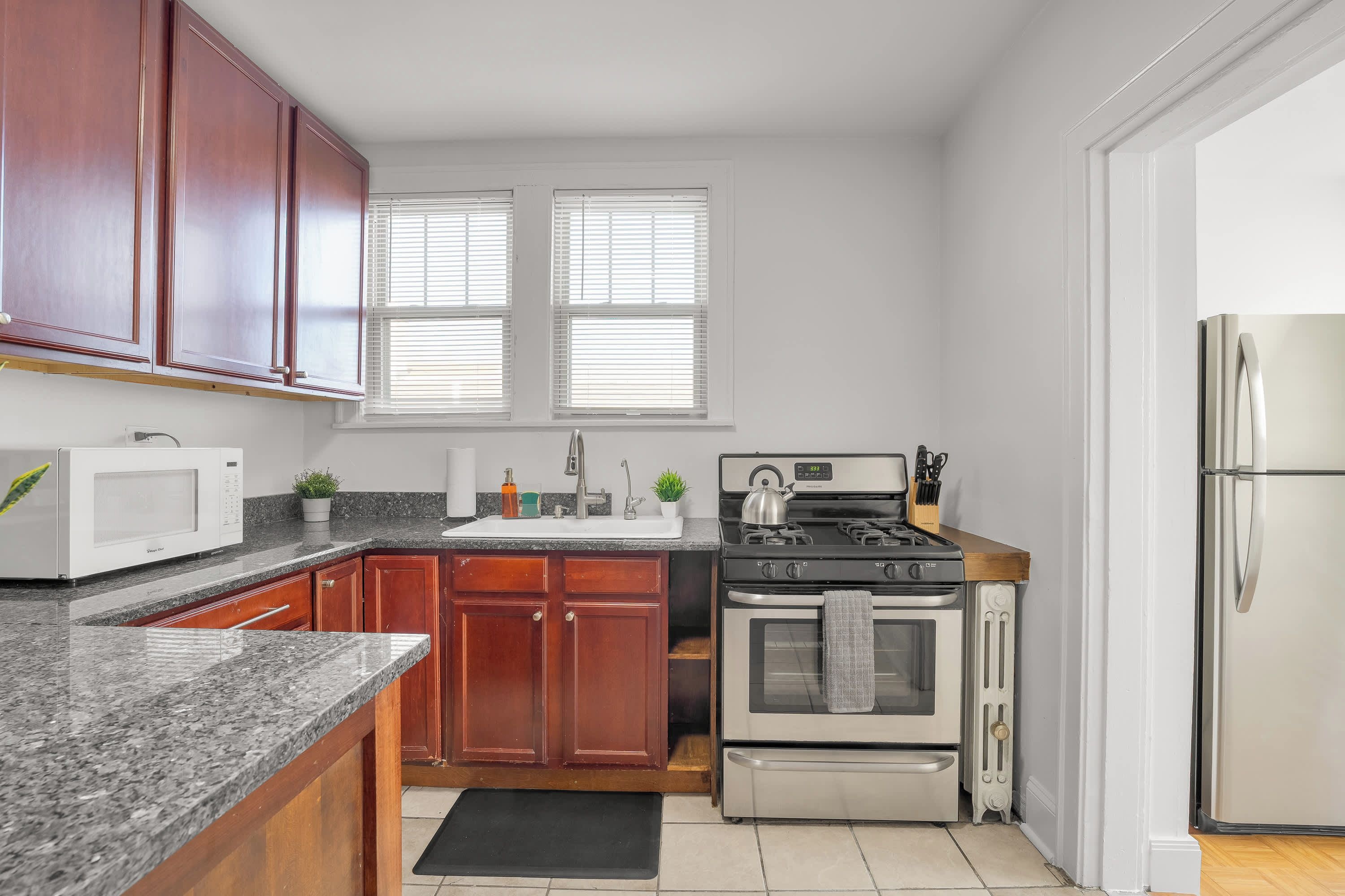 A kitchen with wooden cabinets, a microwave, stove, oven, and a refrigerator.