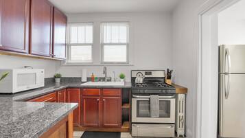 A kitchen with wooden cabinets, a microwave, stove, oven, and a refrigerator.