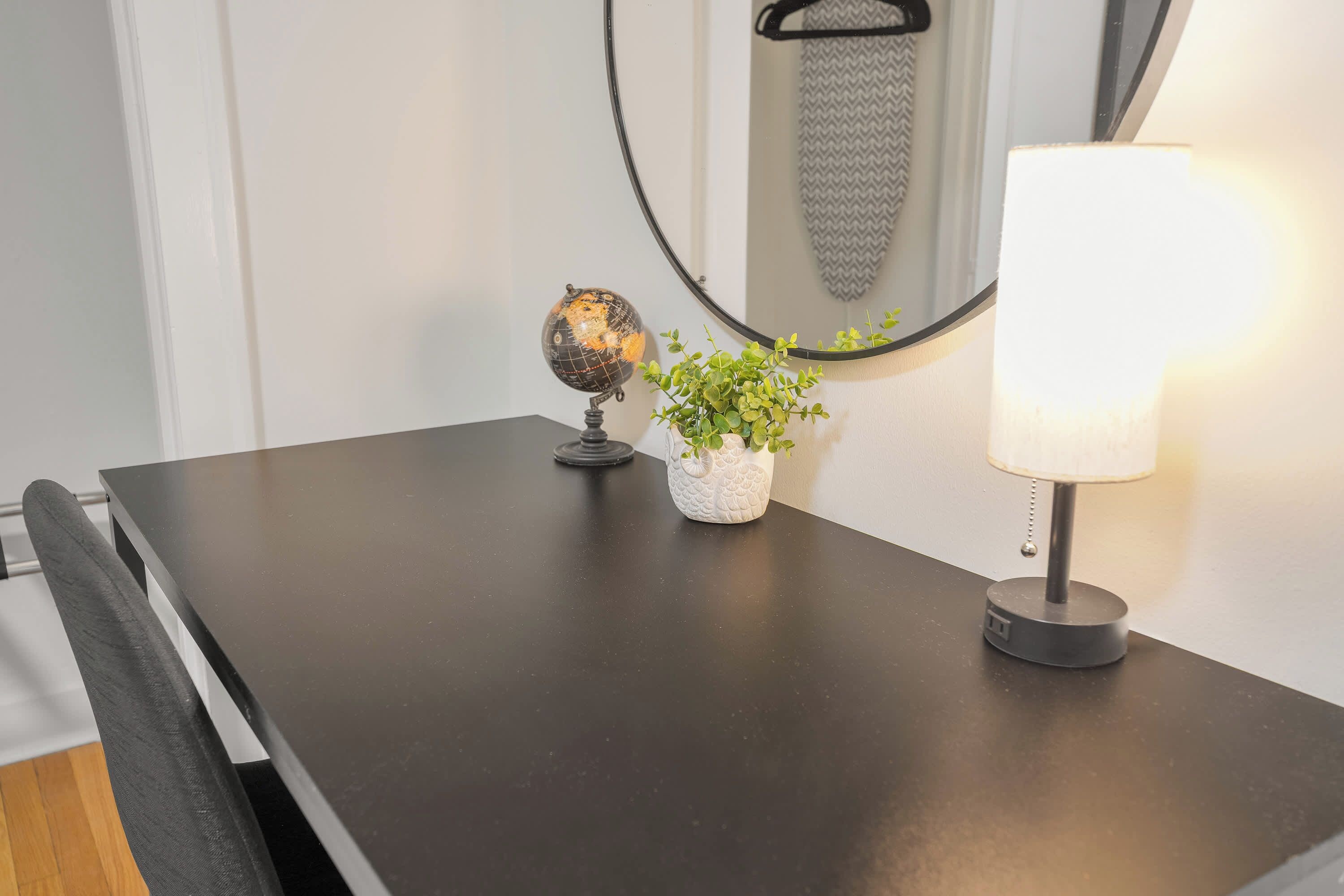 A dark wooden table with a globe, a potted plant, and a lamp.