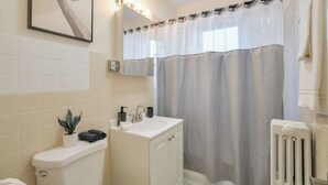 Een badkamer met toilet, wastafel, kast, douchegordijn en een potplant.