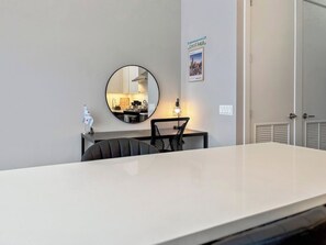 Een moderne hotelkamer met een grote witte tafel, een ronde spiegel, een klein tafeltje met een lamp en een lijst met een afbeelding van Chicago aan de muur.