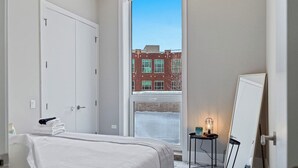 Una habitación de hotel con una cama, ventana, puerta y espejo.