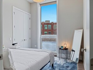 Een hotelkamer met een bed, een raam, een deur en een spiegel.