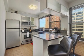 A modern kitchen with stainless steel appliances, a central island, and a view of a cityscape.