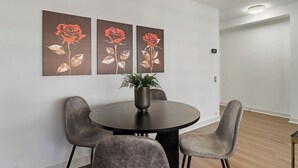 A dining area with a round table, two chairs, and three framed artworks on the wall. - Sunlit 2BR - Fully Furnished & Spacious Apartment (Chicago)