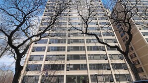 A multi-story building with a central entrance, large windows, and a parking area in front. - Sunlit 2BR - Fully Furnished & Spacious Apartment (Chicago)