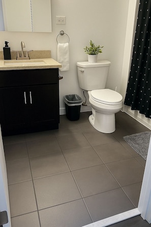 Une salle de bain avec des toilettes, un lavabo et une poubelle.