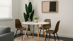 A dining area with a round table, two chairs, a potted plant, and a framed artwork on the wall. - Hyde Park 1BR w/ Charm (Chicago)