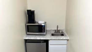 Una kitchenette compacta con microondas, un lavamanos pequeño y lavavajillas.