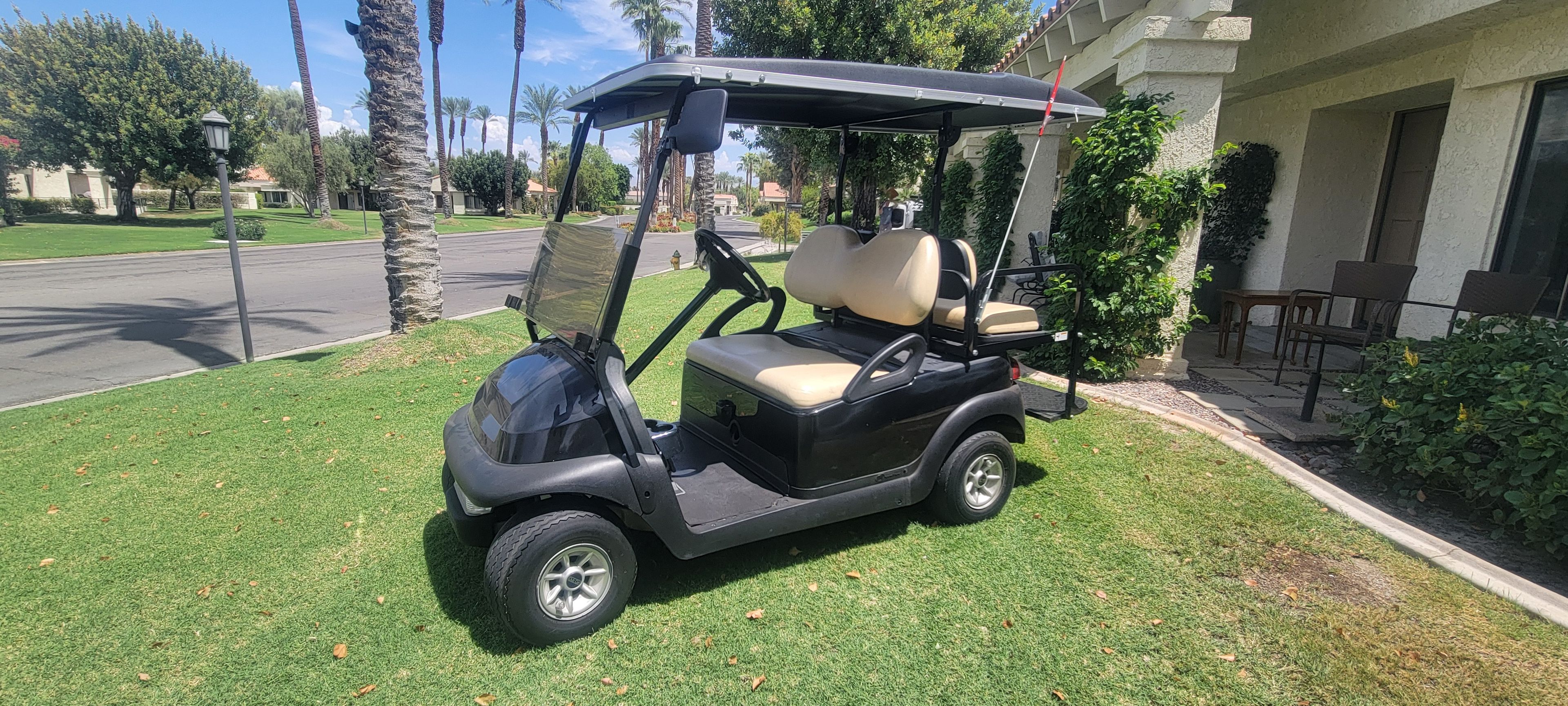 A golf cart parked on a well-maintained lawn with a building in the background.