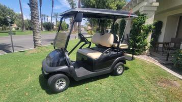 A golf cart parked on a well-maintained lawn with a building in the background.