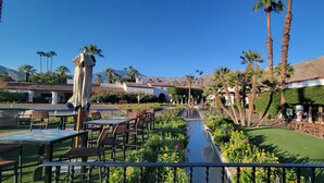 A courtyard with outdoor seating, palm trees, and a view of mountains.