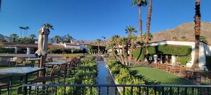 A courtyard with outdoor seating, palm trees, and a view of mountains.