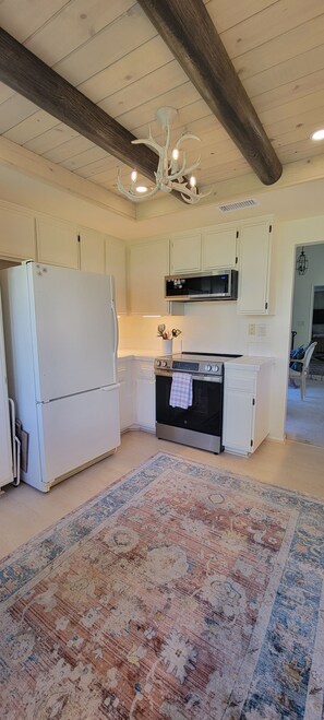 A kitchen with white cabinetry, a stainless steel oven, a microwave, and a chandelier.
