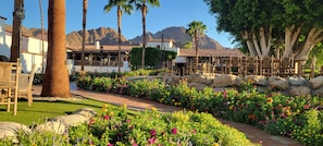 A resort with outdoor seating, a garden with colorful flowers, and a mountainous backdrop.