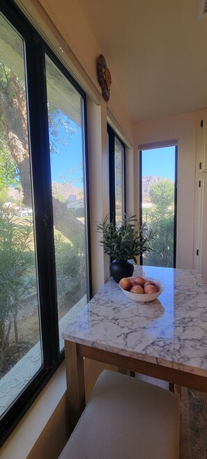 A room with a marble countertop, a bowl of fruit, and a potted plant.