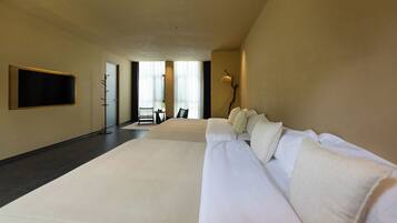 A hotel room with a large bed, a flat-screen TV mounted on the wall, and a seating area with a table and chairs.