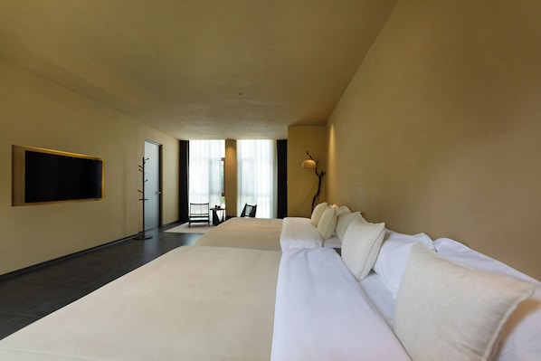 A hotel room with a large bed, a flat-screen TV mounted on the wall, and a seating area with a table and chairs.