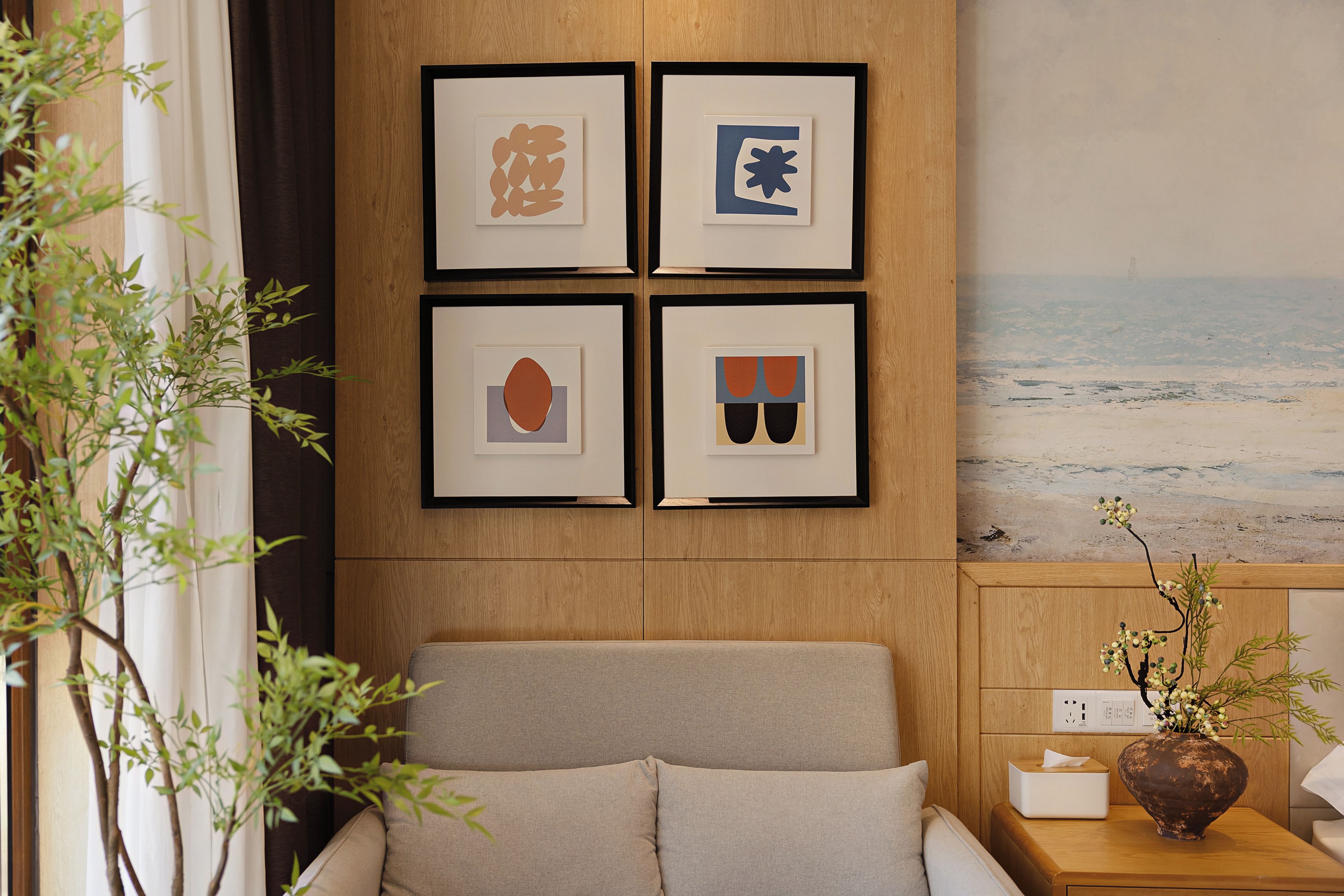 A room with a bed, a wall-mounted artwork, and a view of the beach.