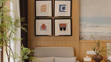 A room with a bed, a wall-mounted artwork, and a view of the beach.