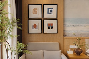 A room with a bed, a wall-mounted artwork, and a view of the beach.