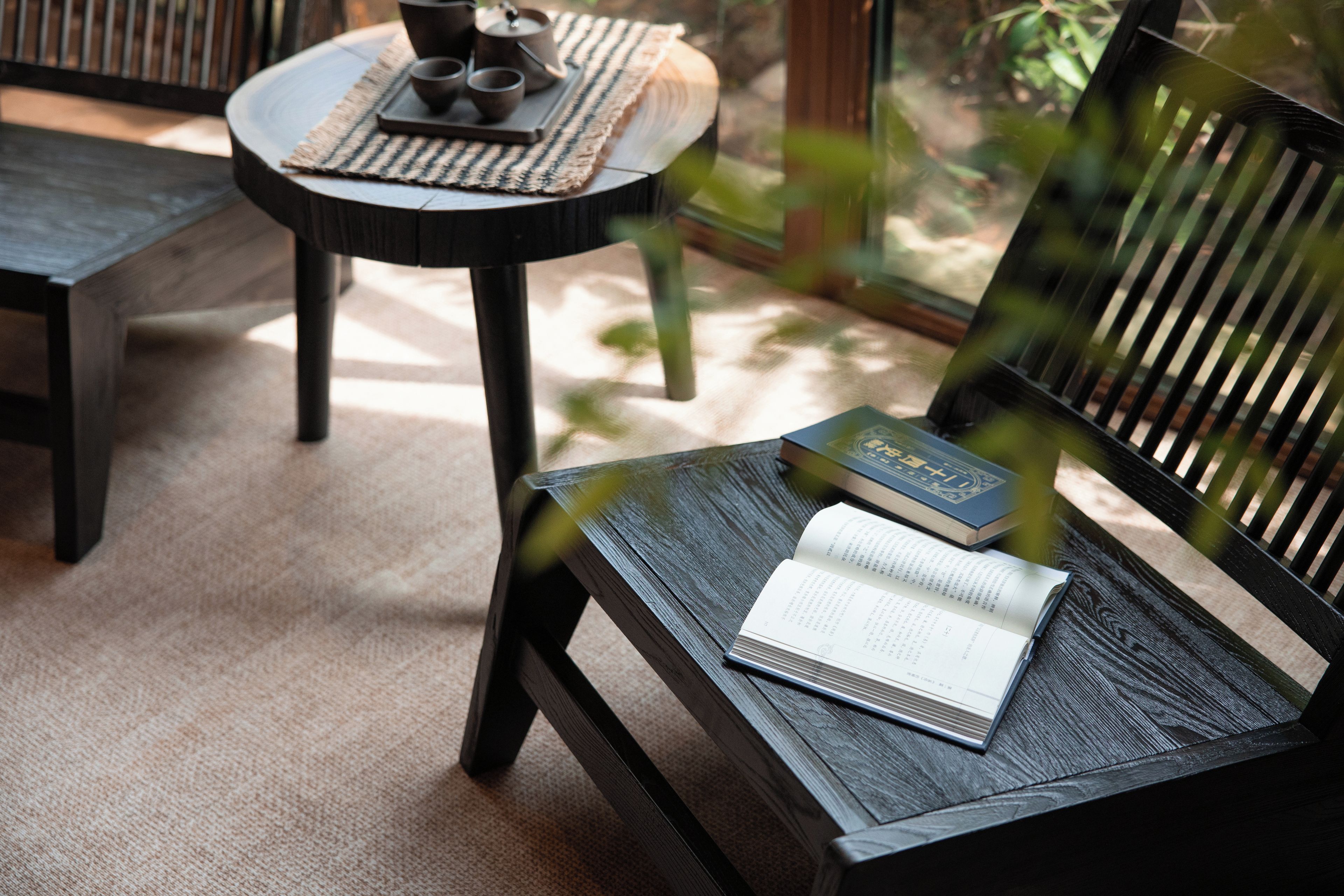 A wooden chair with a book and a teapot on a woven mat.