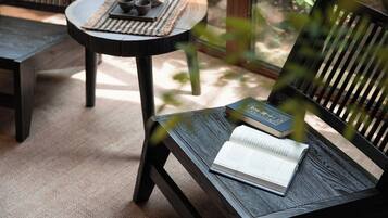 A wooden chair with a book and a teapot on a woven mat.