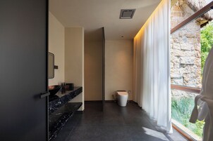 Un baño moderno con encimera de mármol negro, inodoro y ventana con cortinas.