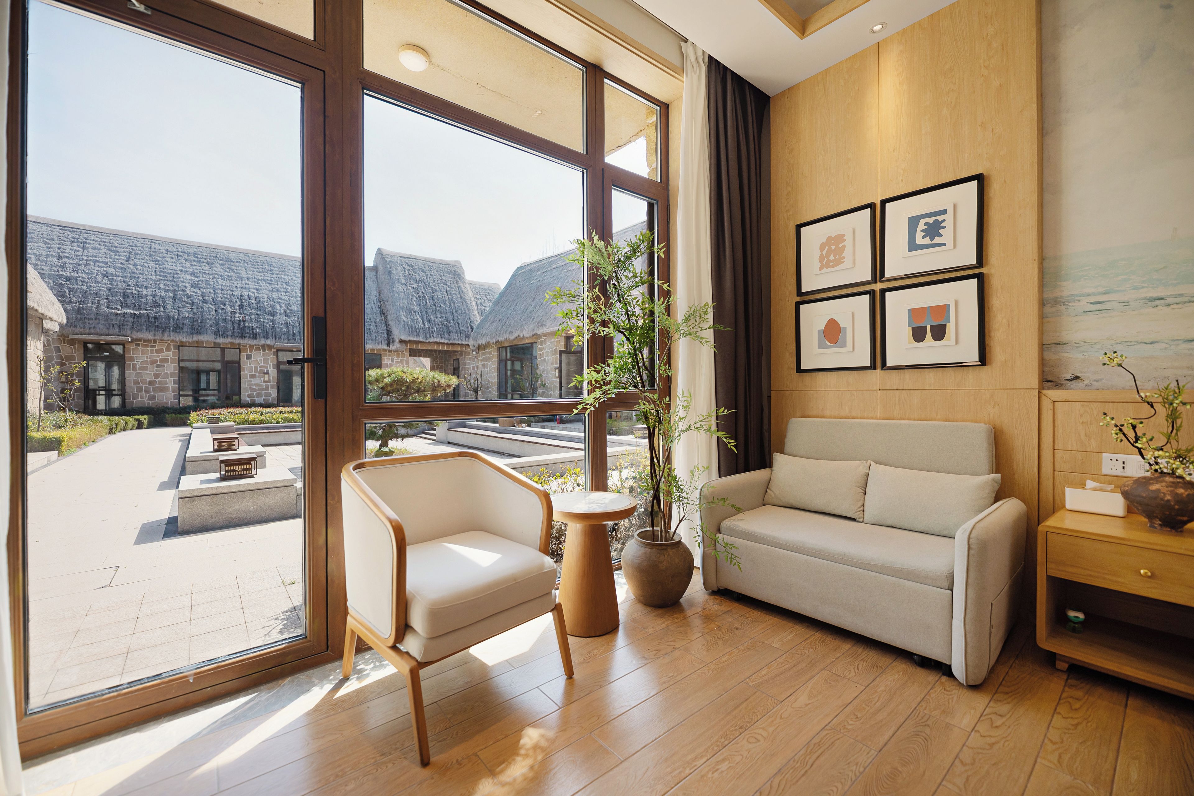 A modern interior with a large window, a sofa, a chair, and a small table.