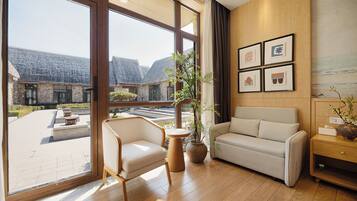A modern interior with a large window, a sofa, a chair, and a small table.