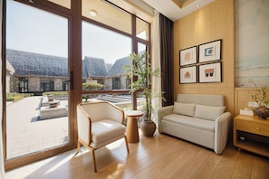 A modern interior with a large window, a sofa, a chair, and a small table.