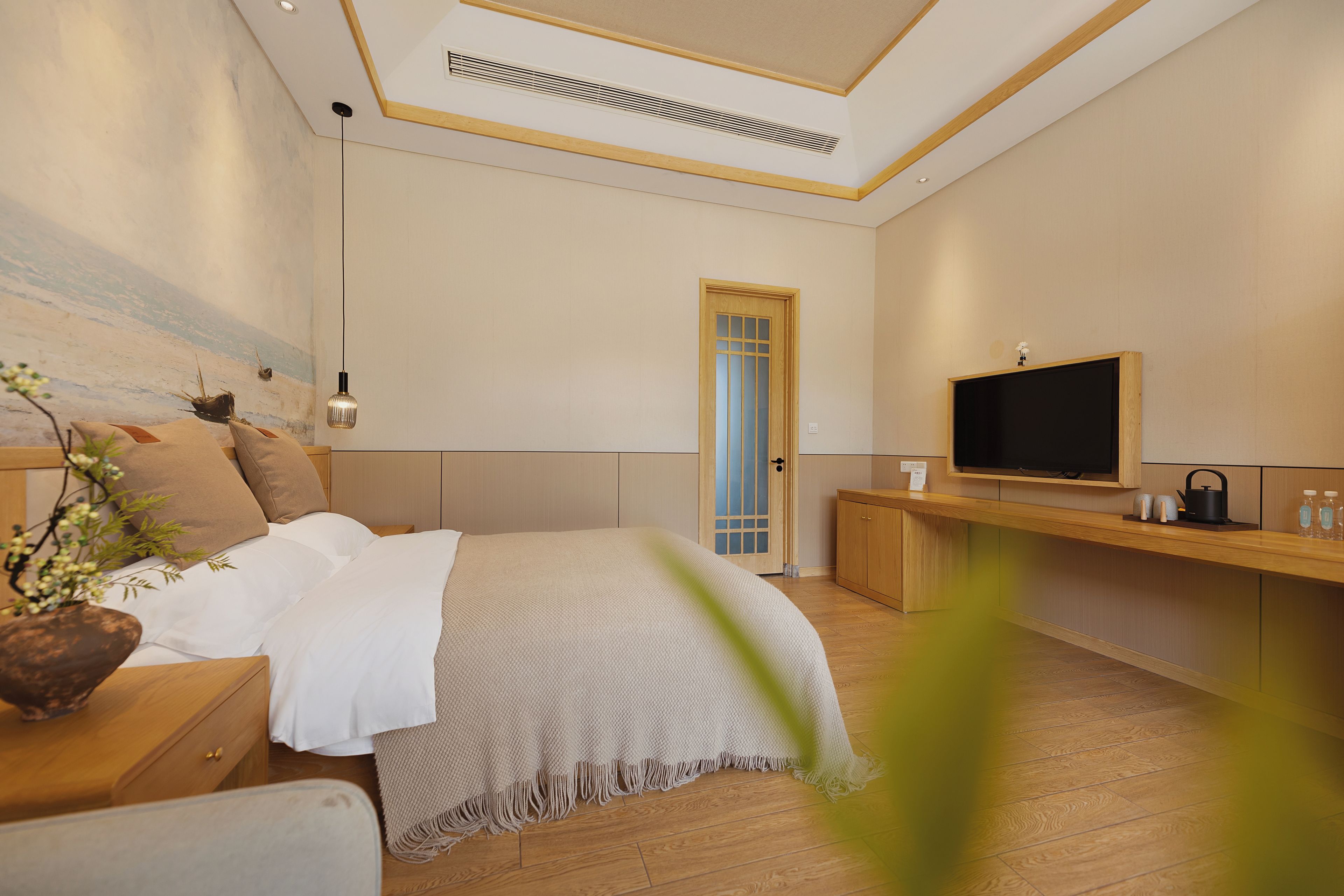 Un dormitorio moderno con cama, mesita de noche, televisor y suelo de madera.