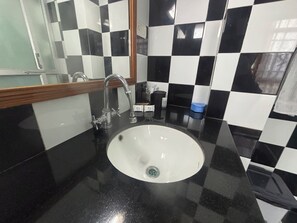 A bathroom with a black and white checkered tile backsplash, a white sink with a single faucet, and a mirror above the sink.
