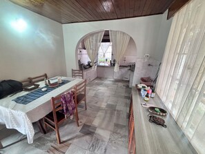 A room with a dining table, chairs, a kitchen area, and a bathroom.