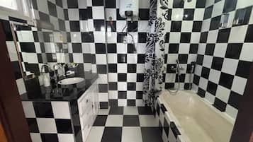 Une salle de bain avec un carrelage à motifs, un lavabo, une douche et des toilettes.