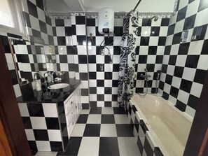A bathroom with a checkered floor, a sink, a shower, and a toilet.