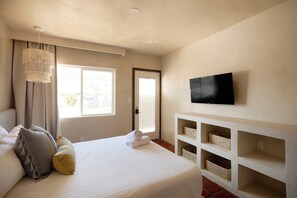 A hotel room with a bed, a television mounted on the wall, and a window with curtains. - Cozy Studio | Beach Just Across the Street (Imperial Beach)