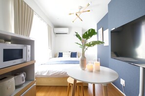 A modern hotel room with a bed, a television, a microwave, a kettle, a table with candles, and a large window. - Lamarie Haneda 403 (Ota Ku)
