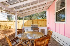 Eine Terrasse im Freien mit Grill, Tisch und Stühlen.