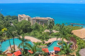 A resort with a large pool, palm trees, and a view of the ocean.