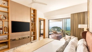 Quarto de hotel com uma cama grande, televisão de tela plana, varanda e um móvel de madeira.