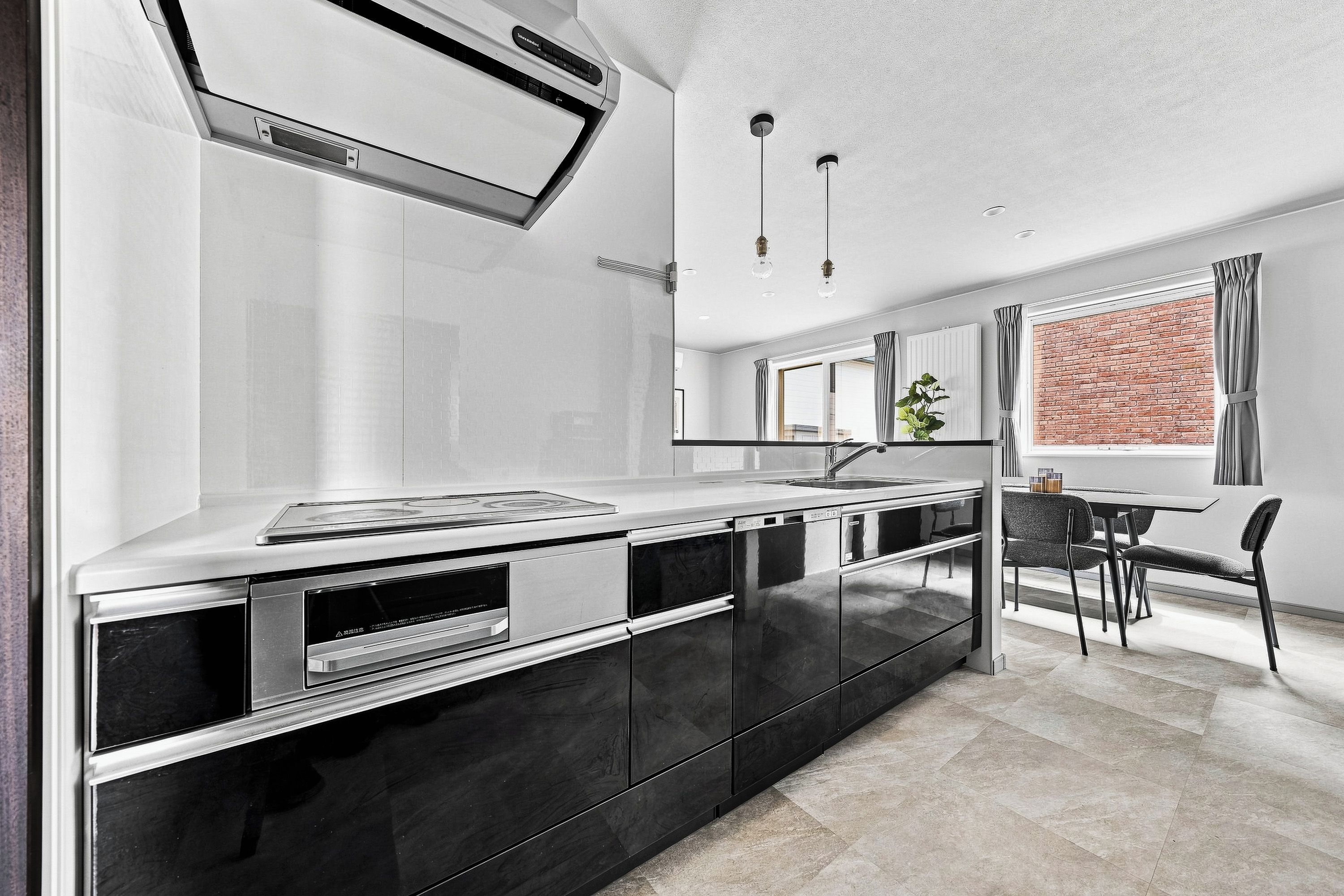 A modern kitchen with a built-in stove, a sink, and a dining area with a table and chairs.