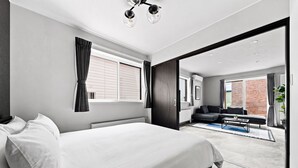 A modern bedroom with a large bed, a sofa, and a view of the outside. - BRIC (Asahikawa)